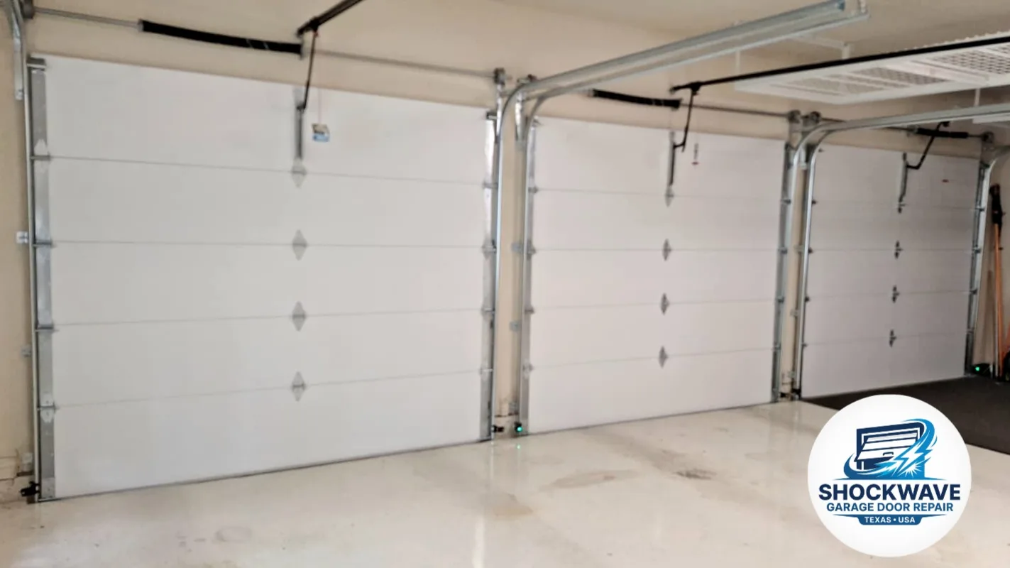 Three white sectional garage doors viewed from inside a clean garage in Shockwave's Austin-area work gallery.